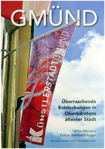 Buchtitelseite des Buchs Gmünd von Ulrike Mengeú. Vor einem blauen Himmel mit Wolken eine Fahne an einer Hauswand links hängend mit der Aufschrift Künstlerstadt Gmünd.